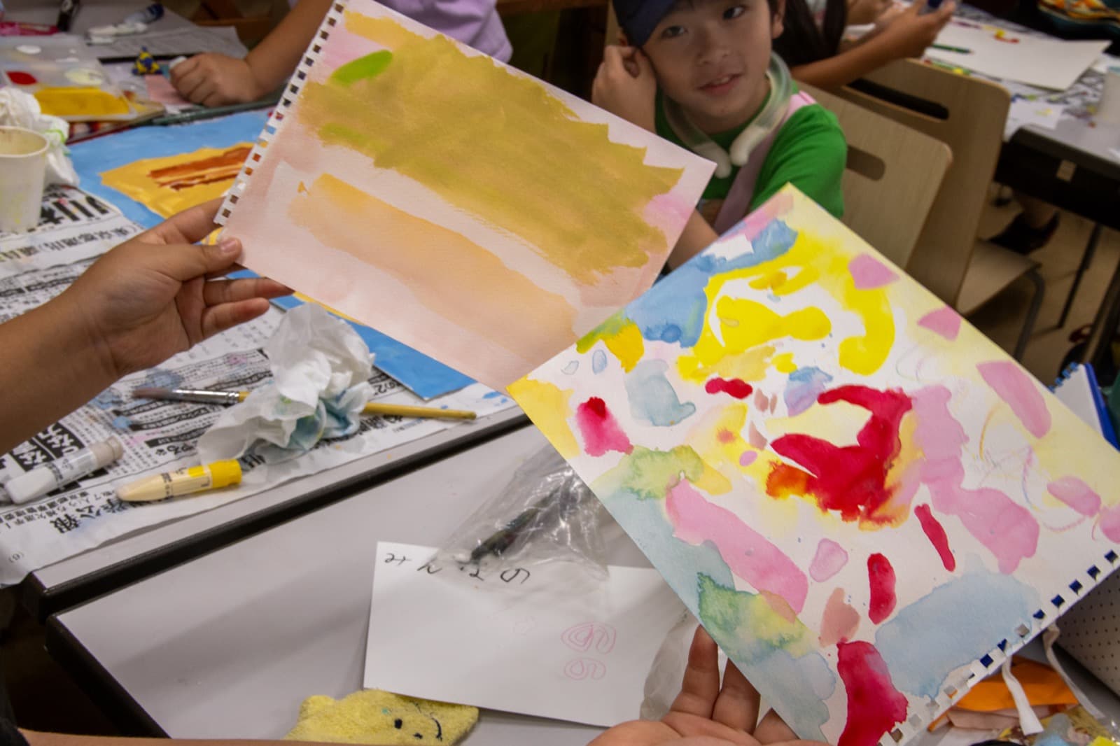 絵の具で制作した作品を見せる子ども