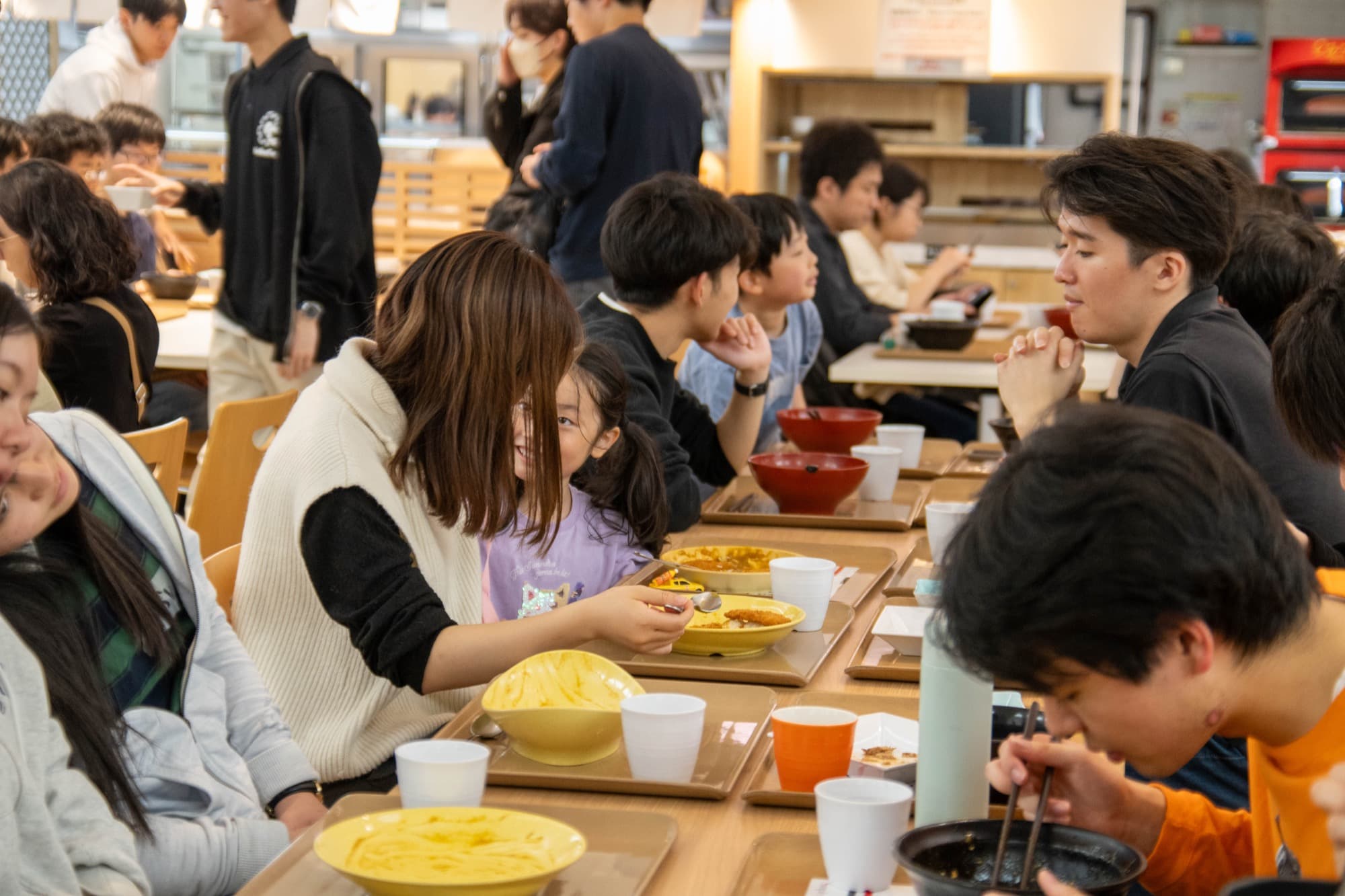 食堂で食卓を囲む子どもと大学生たち