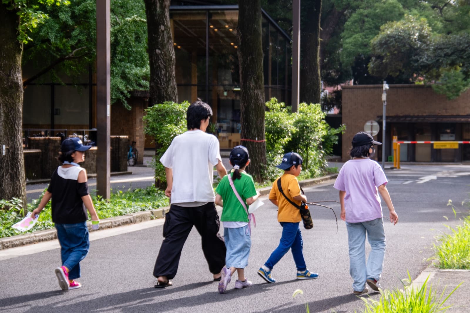 キャンパスの道を歩く子どもと大学生の一行