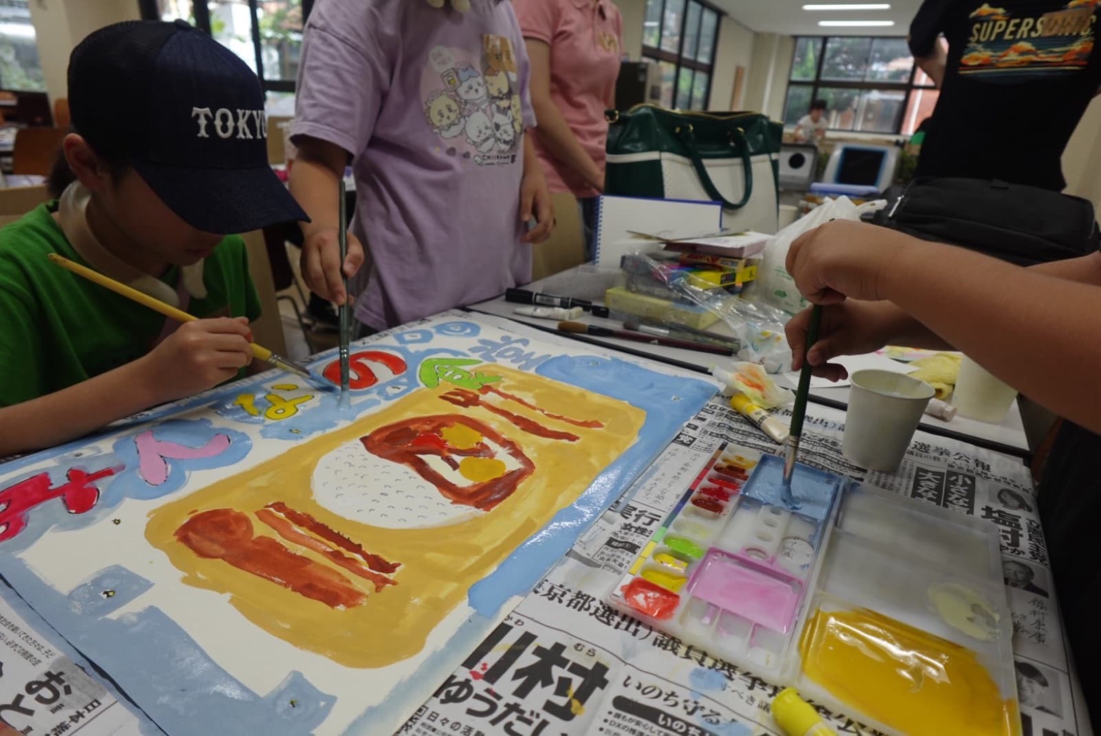 絵の具で絵を描く子どもと大学生