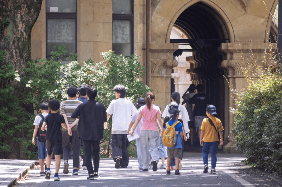 石造りのアーチに向かって、子どもと大人が歩いている