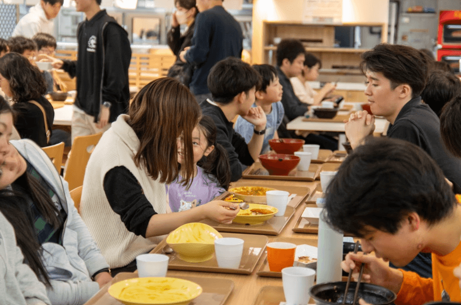 長いテーブルを囲み、子どもと大人が一緒に食事をしている